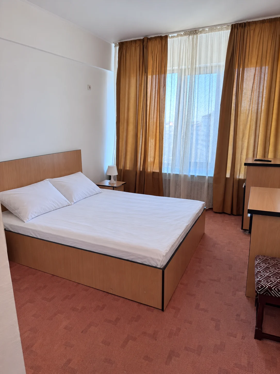 Cameră cu pat matrimonial, lenjerie albă și draperii aurii la Hotel Unirea